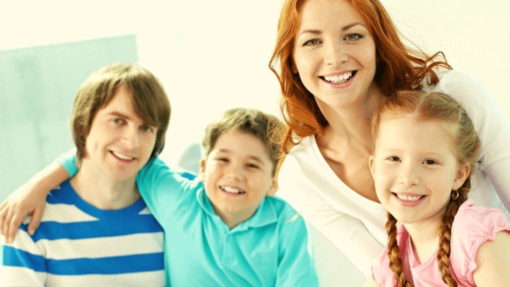 Woman with dentures in Northampton smiling with three kids