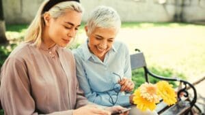 Two women looking at a phone together on a park bench