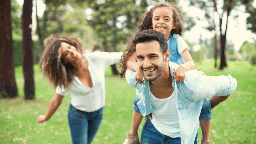 Smiling mother and father playing with their child outdoors after getting dental sealants in Northampton