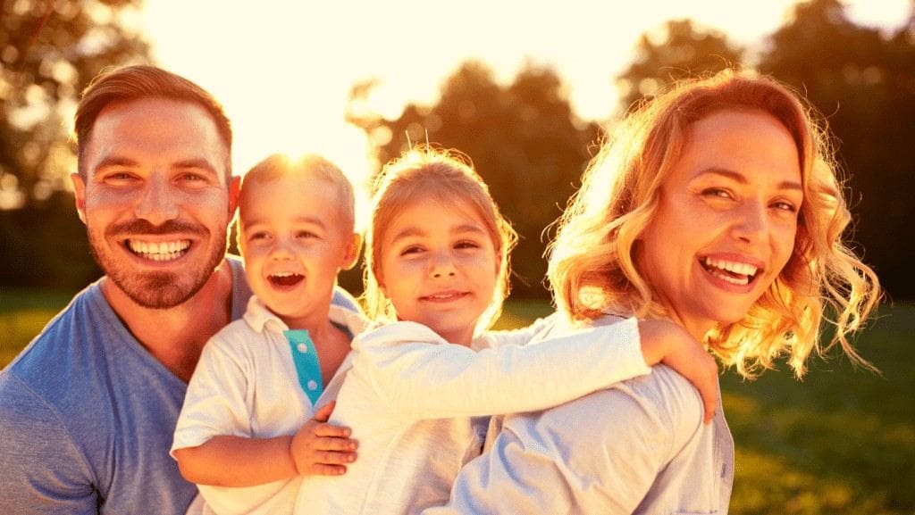 Family of four smiling outdoors at sunset after receiving digital dental x rays