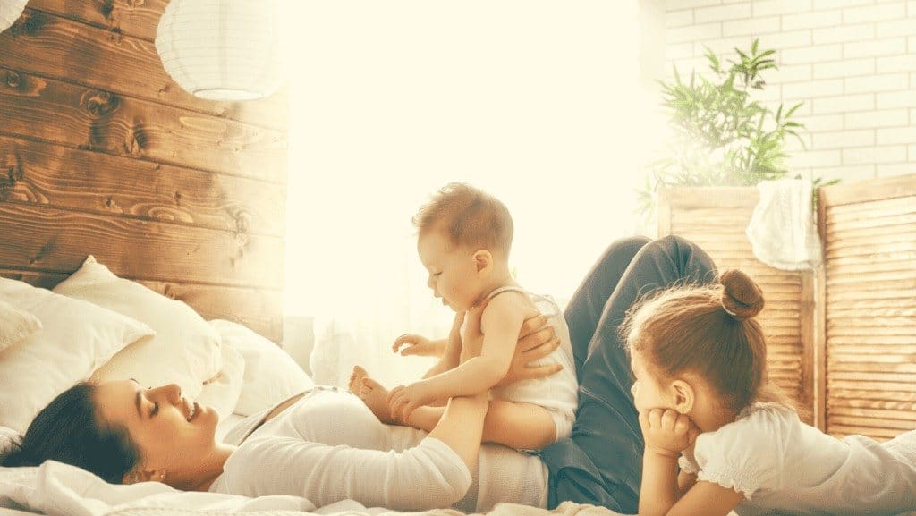 Mother lounging in bed with her two very young children