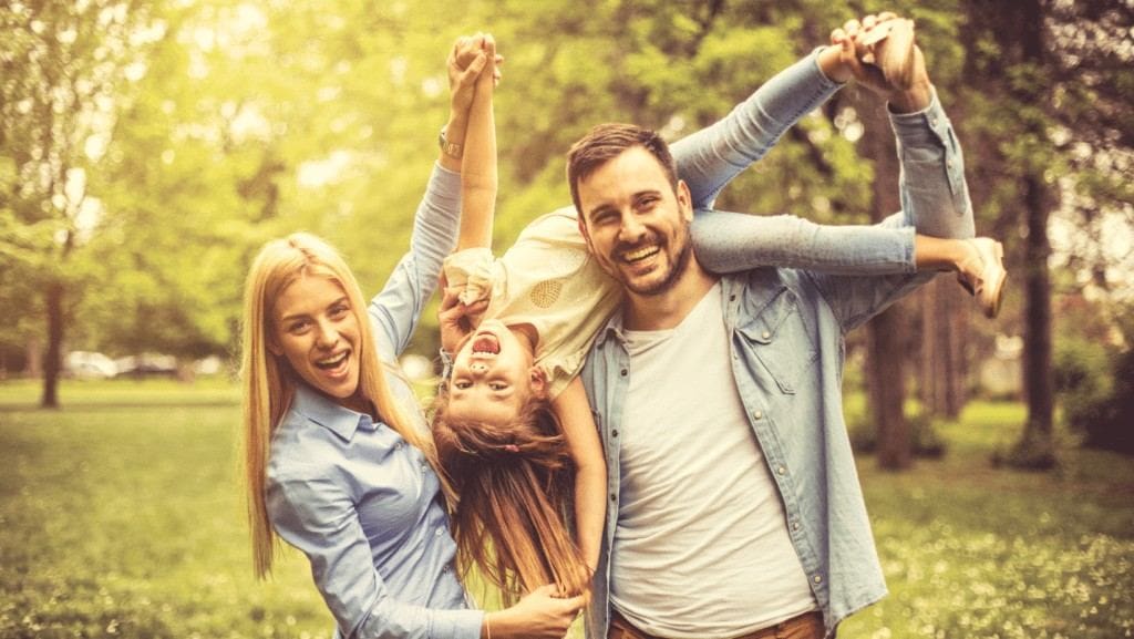 Family laughing with their daughter outdoors