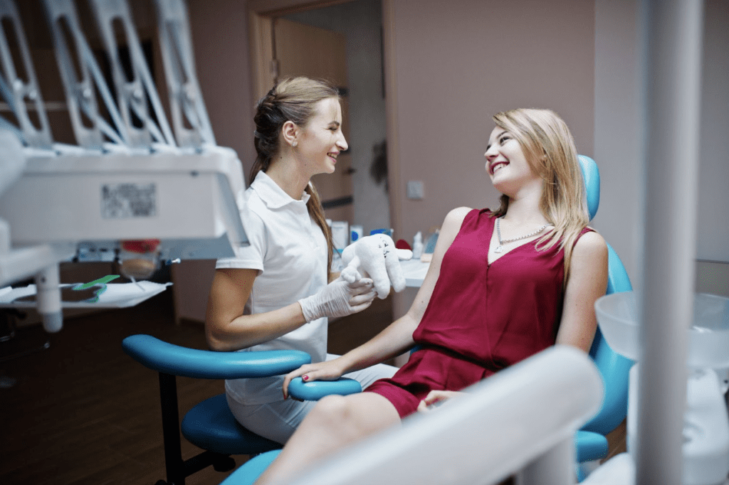 patient sitting on dental chair and smiling at dentist