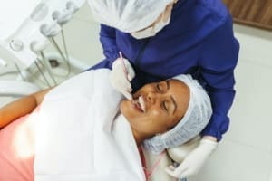 Woman in dental chair receiving professional teeth whitening from cosmetic dentist