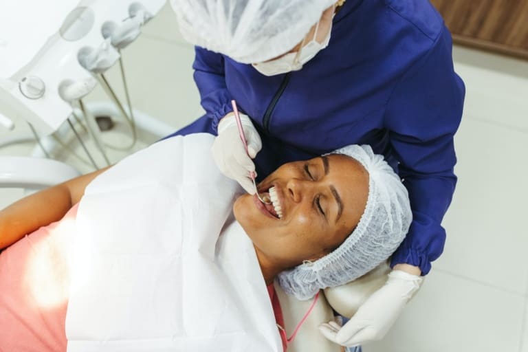 Woman in dental chair receiving professional teeth whitening from cosmetic dentist