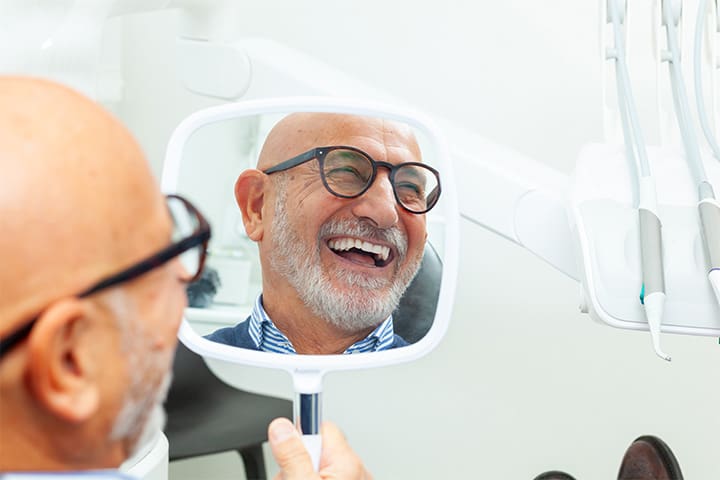 Man with glasses smiling at reflection in mirror