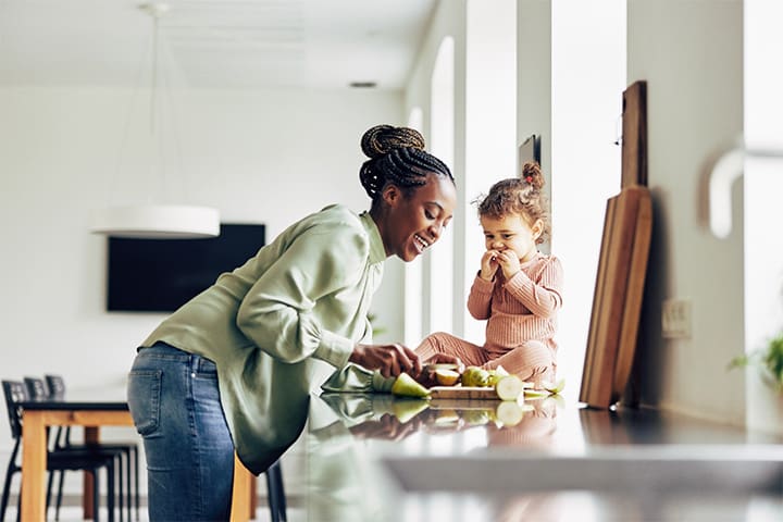 Mom and daughter snacking on apple in kitchen
