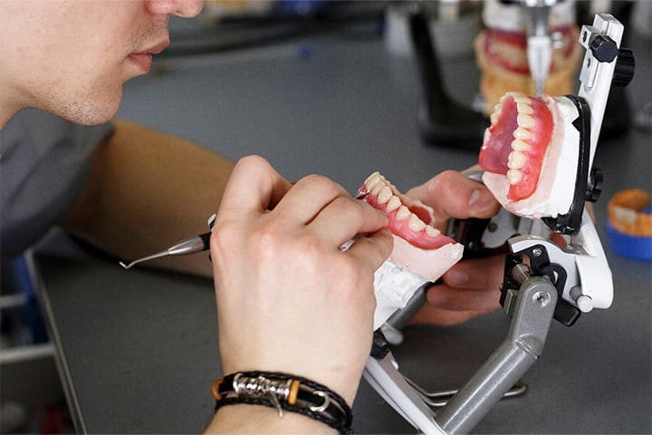 Lab technician building a denture in the lab