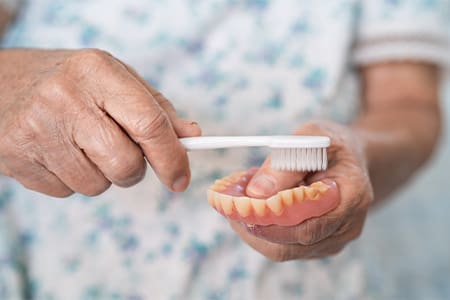 Person cleaning their dentures.