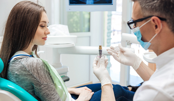 A dentist showing a dental implant to his patient.