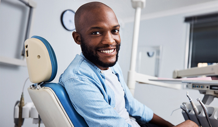Bearded man sitting in dental chair smiling.