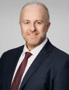 Profile image of Dr. Konstantinos Vazouras smiling in a suit and tie.