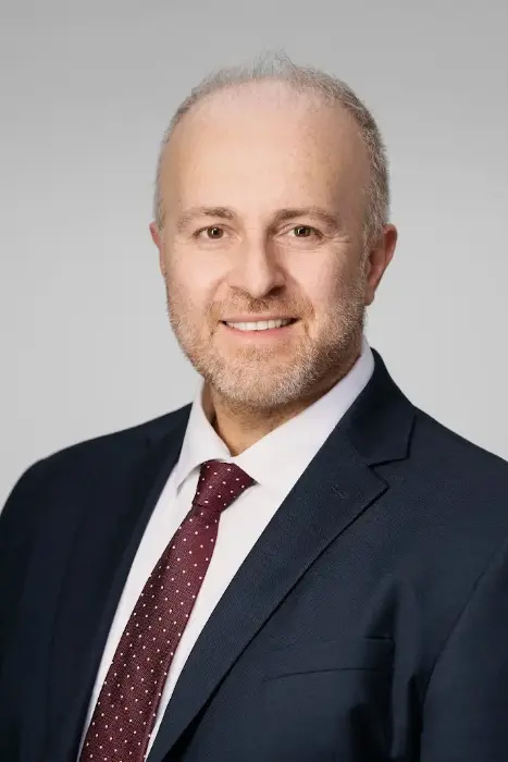 Profile image of Dr. Konstantinos Vazouras smiling in a suit and tie.