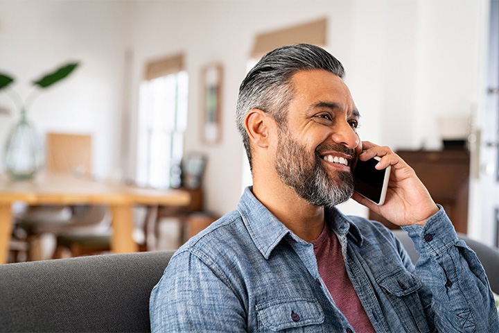 Man smiling while talking on phone.