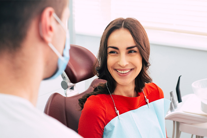 Woman smiling at dentist while sitting in treatment chair.