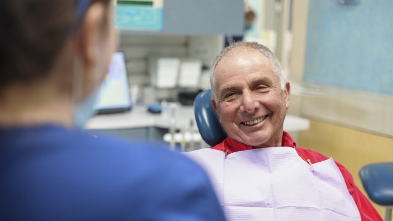 A smiling man seated in a dental chair at Northampton Dental Specialists Group, showcasing a positive dental experience.